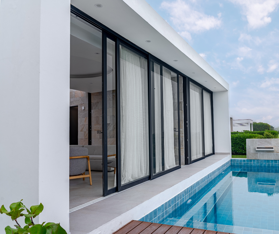 Mamparas corredizas de PVC negro para integrar sala y piscina en casa de playa moderna en Asia, Lima. Carpintería premium Swedish House.